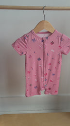 Video of a pink baby romper with colorful girly patterns hanging on a rack