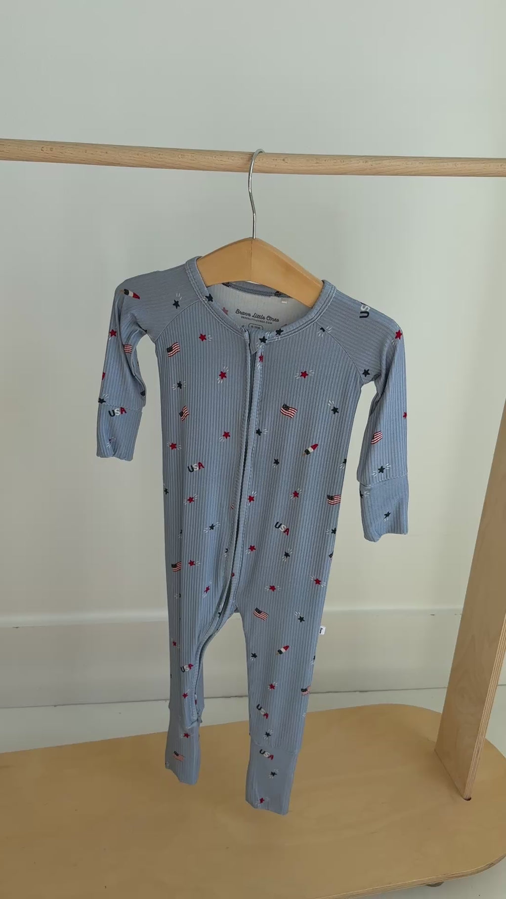 Blue baby onesie with star and flag pattern hanging on a rack