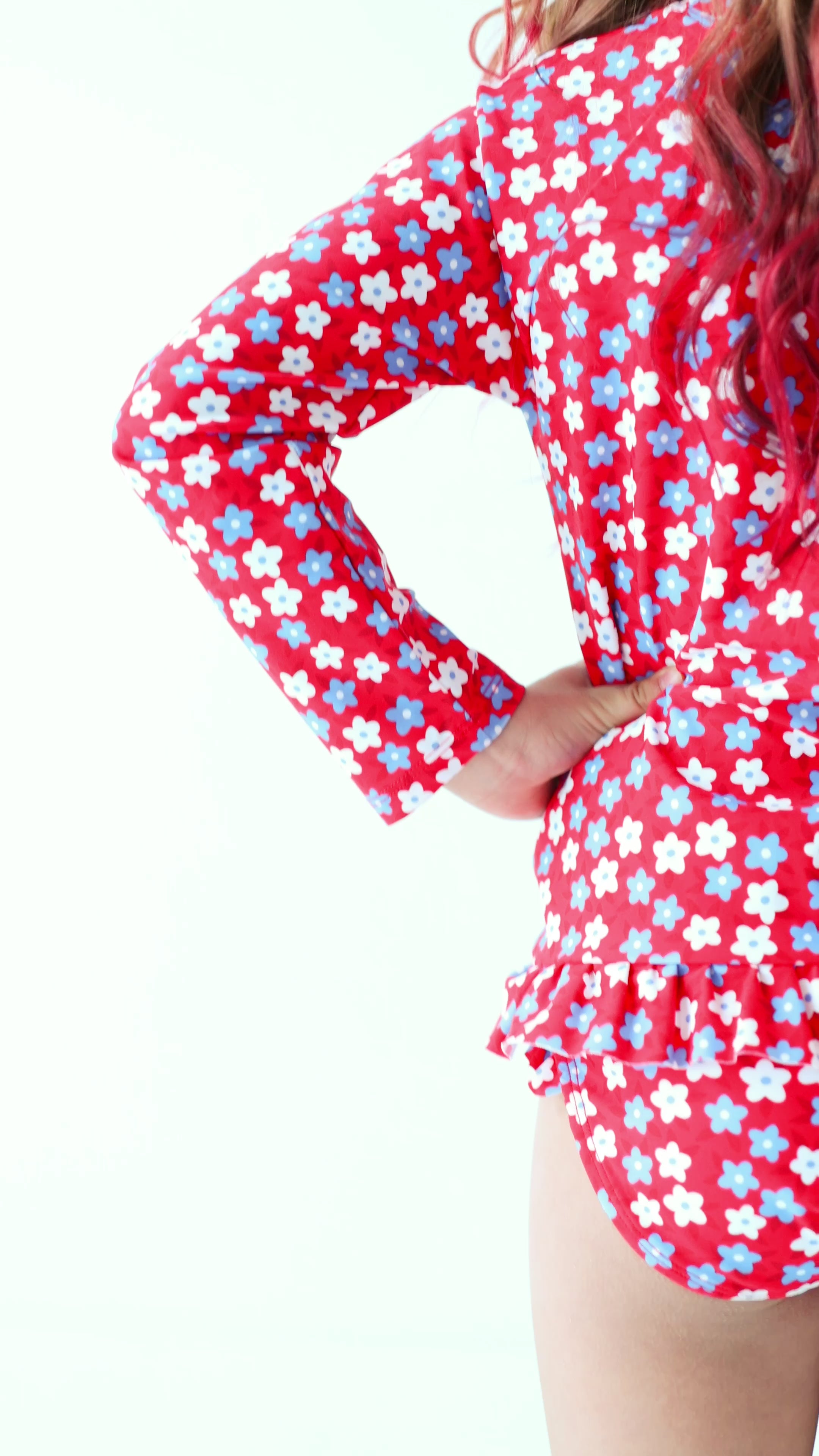 Video of a young girl wearing a red and white floral swimsuit on a white background