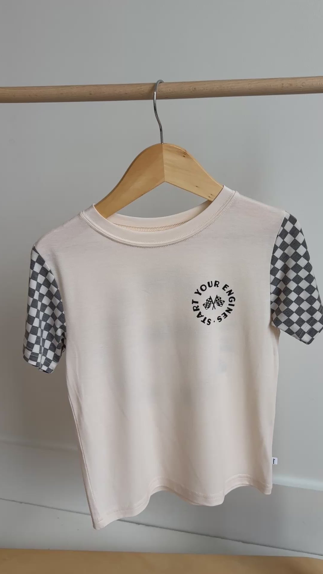 White t-shirt with checkered sleeves hanging on a rack