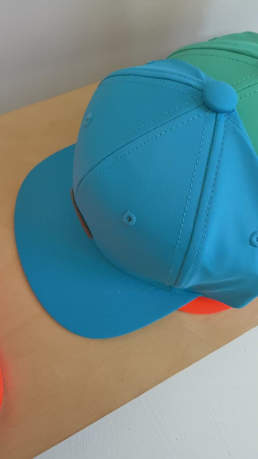 Video of a colorful set of trucker hats on a wooden plank