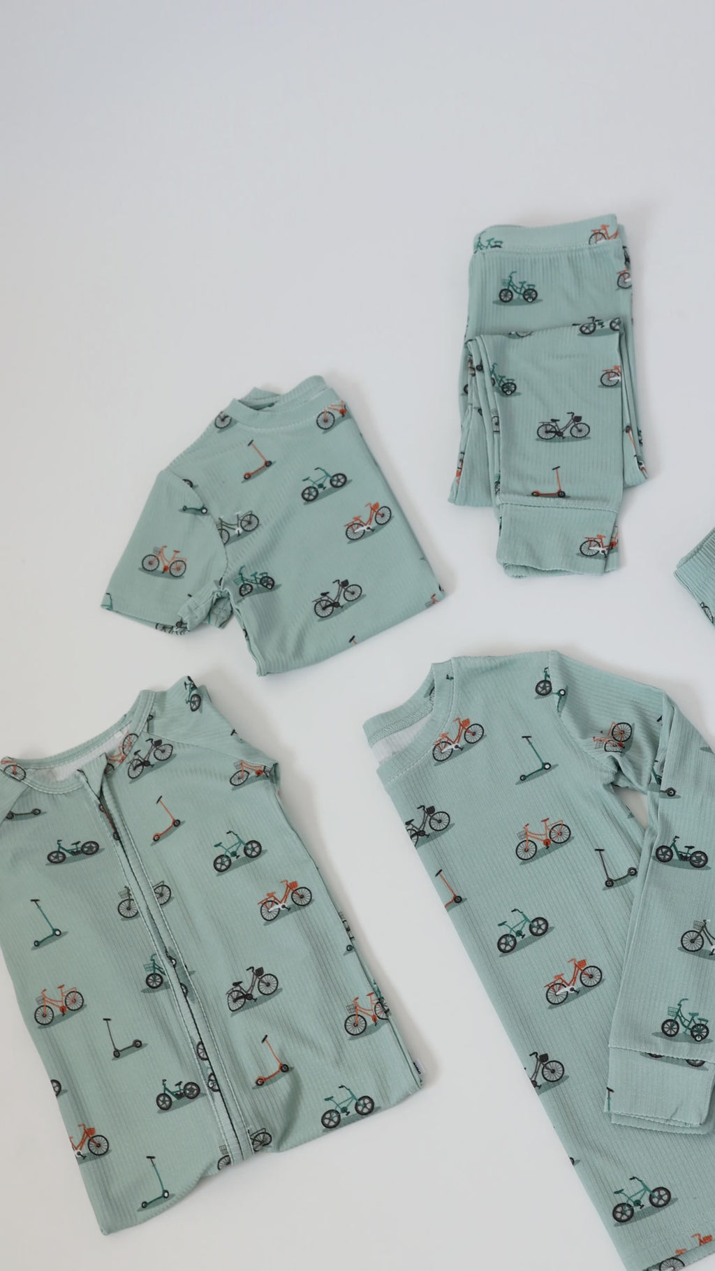 Video of light blue baby pajama sets with bicycle and scooter patterns on a white background