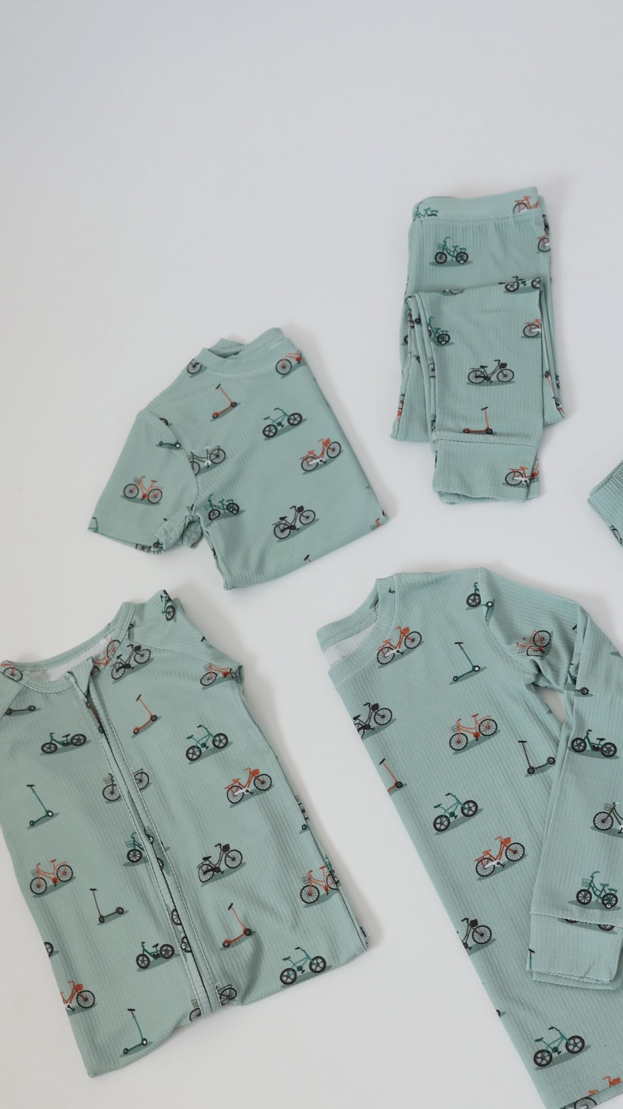 Video of light blue baby pajama sets with bicycle and scooter patterns on a white background