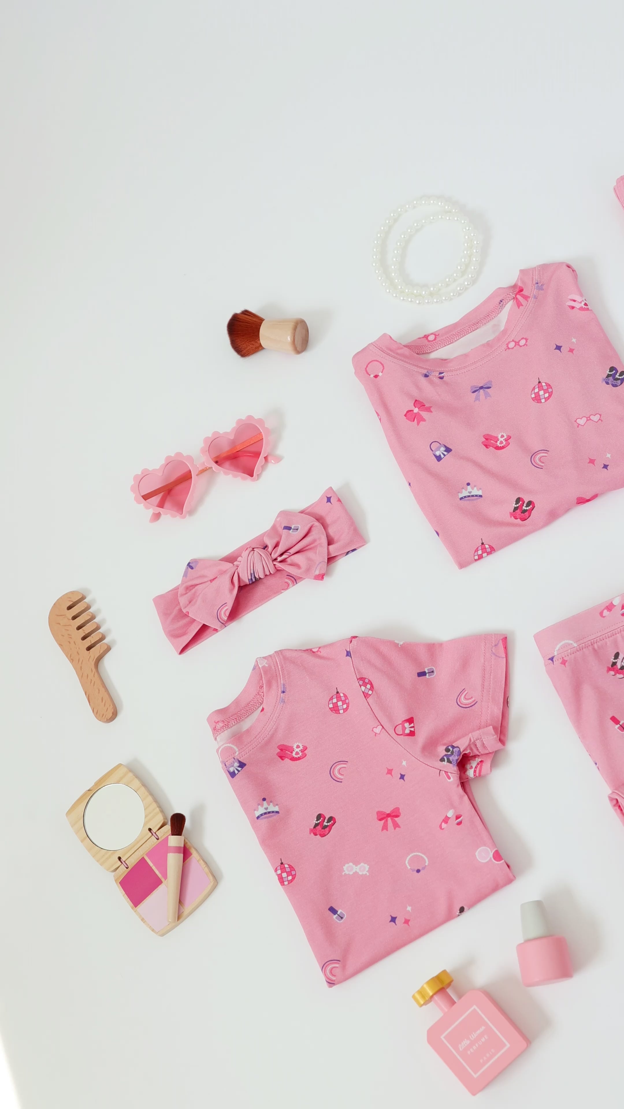 Video of a collection of pink children's pajamas and accessories on a white background