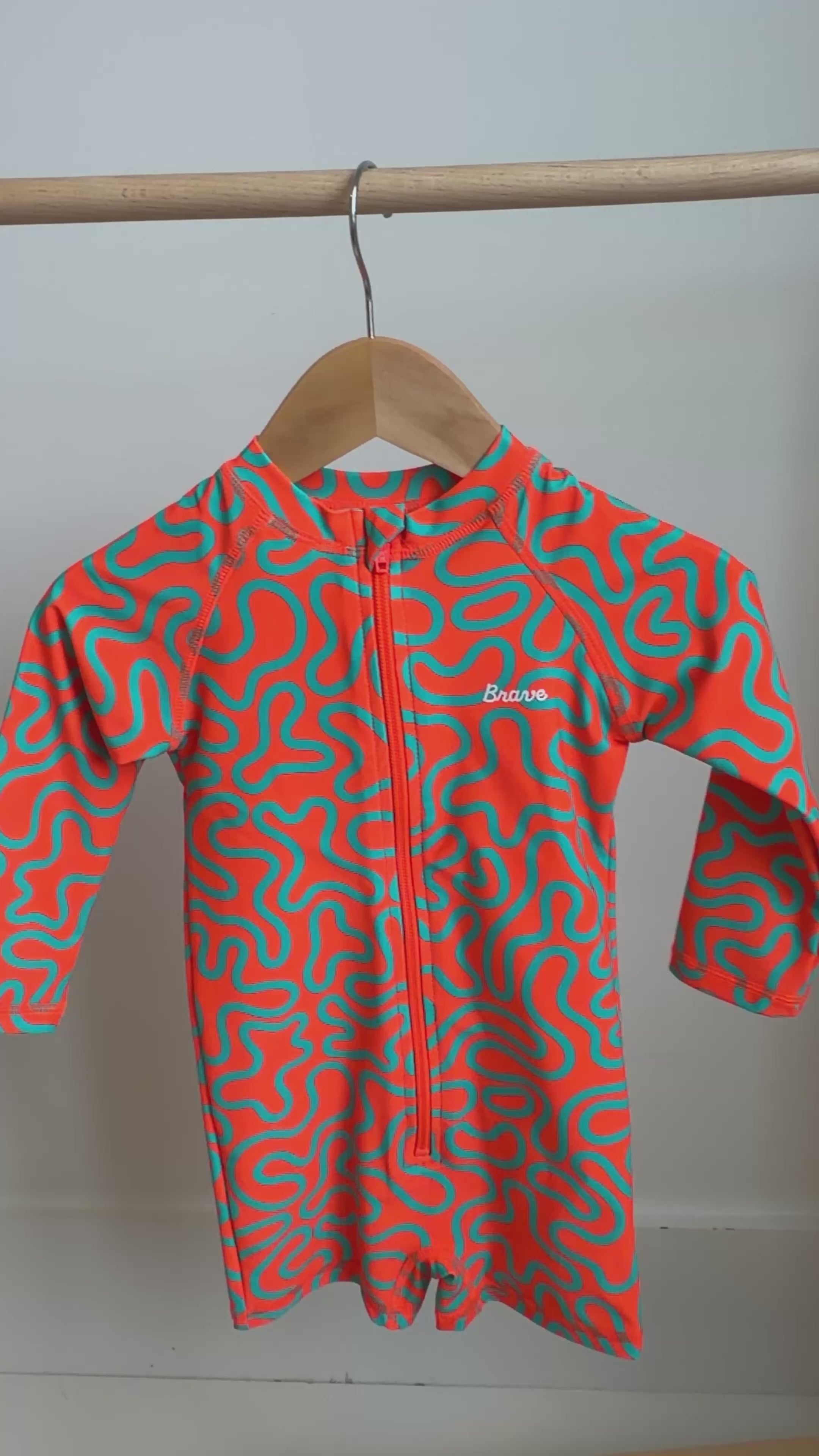 Orange and blue squiggly patterned boy swimsuit hanging on a rack