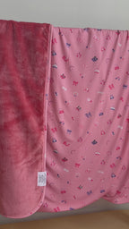 Pink blanket with small girly patterns draped over a hanging rack