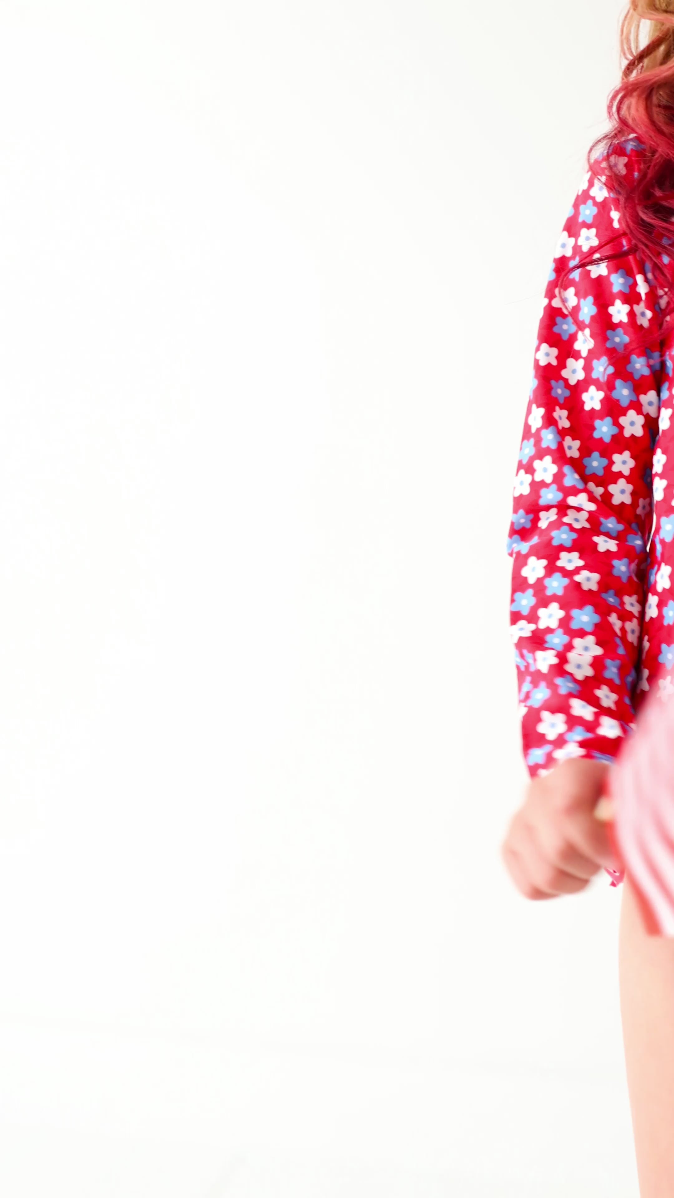 Video of a young girl wearing a red and white floral swimsuit, holding small American flags, on a white background