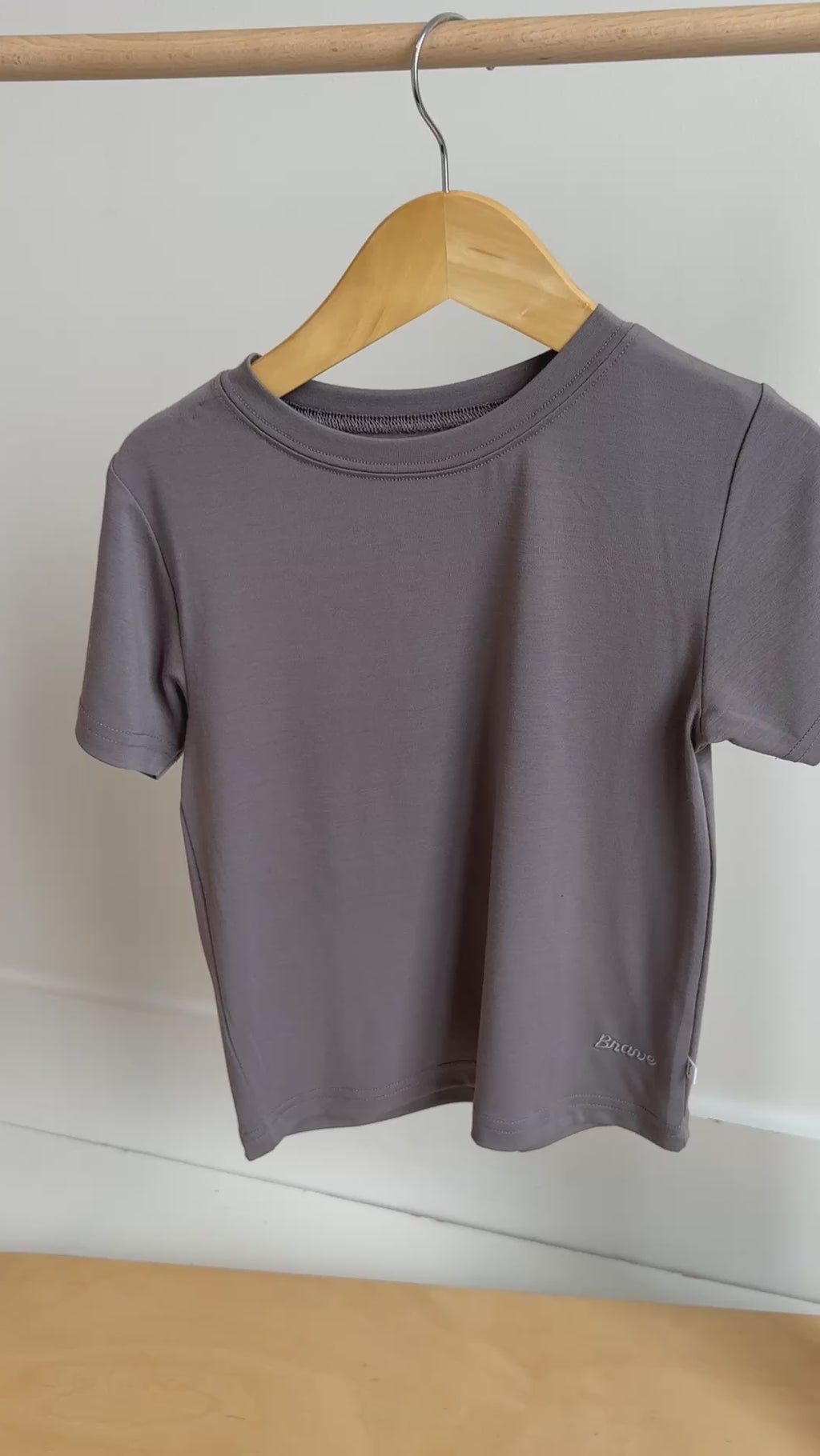 Plain dark gray t-shirt hanging on a rack